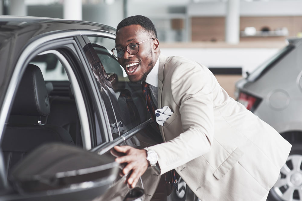 african man looking at a new car at the car dealership.